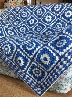 a blue and white crocheted blanket sitting on top of a bed