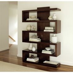 a book shelf filled with books and vases on top of each other in a living room