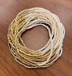 "IVORY AND GOLD Simplicity shines in this extra-long wristlace, a 2-in-1 wrap bracelet and necklace that can be worn several ways. A rich variety of bead textures, shapes, and finishes -- luminous, translucent ivory \"pearls,\" iridescent ivory tubes, shiny opaque ivory bead, matte ivory rocailles, transparent gold cubes, metallic gold beads in three shapes and sizes -- takes this simple two-color item to the next level, a beautiful, delicate piece to wear with everything. . Custom sizing, made Elegant Multi-strand Faceted Beads Bracelets, Elegant Multi-strand Beaded Bracelets With Faceted Beads, Gold Multi-strand Beaded Bracelets For Layering, Gold Bracelets With Round Beads For Layering, Gold Multi-strand Hand-strung Jewelry, Hand-strung Multi-strand Gold Jewelry, Hand-strung Gold Beaded Bracelets For Parties, Gold Adjustable Double Strand Bracelet, Elegant Wrap Bracelet With Faceted Beads