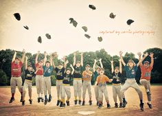 a group of young boys standing on top of a baseball field with their hands in the air