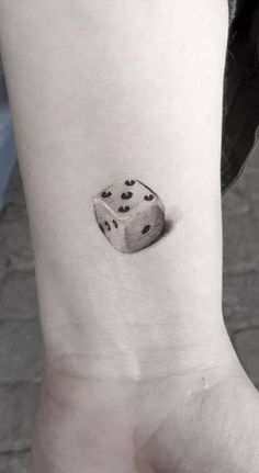 a black and white photo of a dice tattoo on the left inner arm, with dots all over it