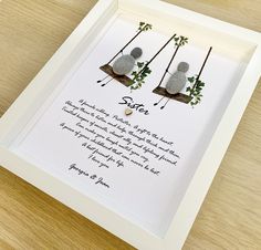 two rocks sitting on top of a wooden table next to a white framed paper with writing