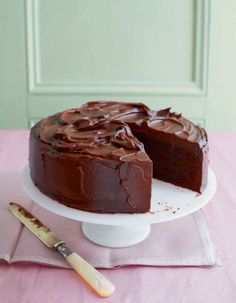 a chocolate cake with one slice missing from it on a plate next to a knife