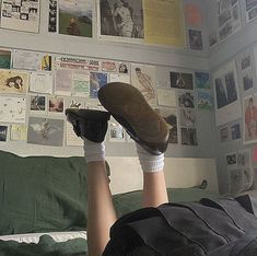 a person laying on top of a bed with their feet propped up against the wall