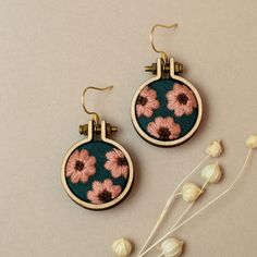 two earrings with pink flowers on them next to white flowers