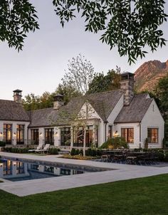 a large white house with a pool in the front yard and landscaping around it at dusk