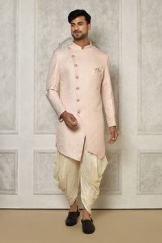 Baby pink sherwani with all over floral mandala pattern. Paired with cream dhoti pant.
Components: 2
Pattern: Woven
Type Of Work: Floral Mandala
Neckline: Stand Collar
Sleeve Type: Full Sleeves
Fabric: Sherwani: Jaquard, Dhoti Pant: Cotton Silk
Color: Pink
Other Details: 
Closure: Front buttons
Embellished brooch detailing
Asymmetric hem
Occasion: Sangeet - Aza Fashions Pink Sherwani For Diwali And Traditional Ceremonies, Pink Sherwani With Zari Work For Traditional Ceremonies, Pink Sherwani For Traditional Ceremonies And Eid, Pink Sherwani For Festive Traditional Ceremonies, Festive Pink Sherwani For Traditional Ceremonies, Pink Sherwani With Pallu For Traditional Ceremonies, Traditional Pink Sherwani For Navratri, Pink Fitted Kurta For Traditional Ceremonies, Pink Traditional Drape Bandhgala For Diwali