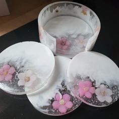 four plates with pink flowers on them sitting on a black counter top next to each other