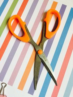 two pairs of scissors sitting on top of a striped table cloth next to some scissors