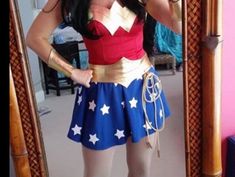 a woman in a wonder costume taking a selfie with her cell phone while standing in front of a mirror