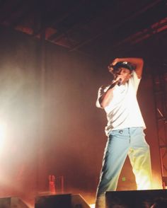 a man standing on top of a stage with his arms up in front of him