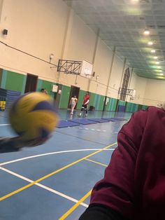 a person is throwing a ball in an indoor basketball court while others are on the other side