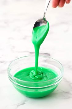 someone is dipping green liquid into a bowl