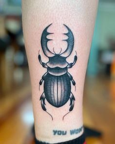 a black beetle tattoo on the leg