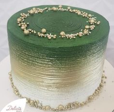 a green and white cake with beads on it's side, sitting on top of a table