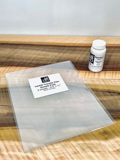 an acrylic adhesive sits on the edge of a wooden table next to a bottle of glue