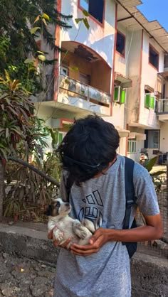 a person holding a small dog in front of a building with balconies on it