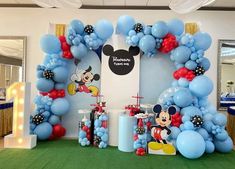 a mickey mouse balloon arch is decorated with blue and red balloons