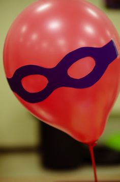 a red balloon with a purple mask on it's head is sitting on a table