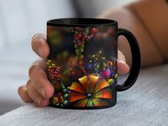 a person holding a black coffee mug with colorful flowers on it