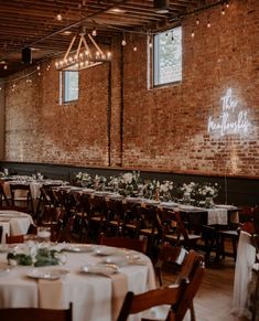 tables and chairs are set up in an old brick room with white tablecloths