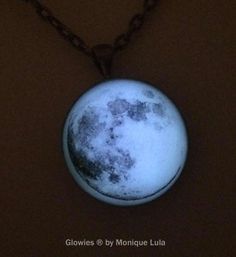 the moon is glowing in the night sky on a necklace with chains hanging from it