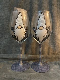 two wine glasses decorated with an image of a gnome and snowflake on them