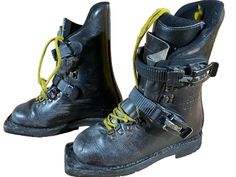 two black boots with yellow laces on the bottom and one is worn in leather