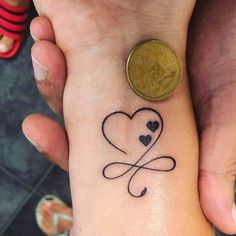 two people holding hands with tattoos on their wrists and one has a coin in the other hand