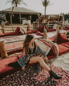 a woman sitting on top of a red rug