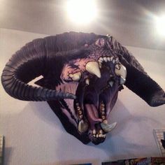 an animal's head mounted on the wall with long horns and large teeth is shown