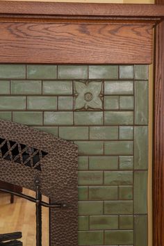 a fireplace with a green brick wall and wooden frame