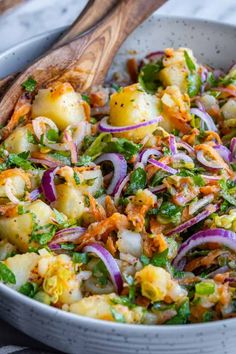 a white bowl filled with salad and wooden spoon