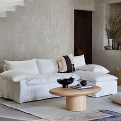 a living room with a white couch and pillows on the back of it's sofa