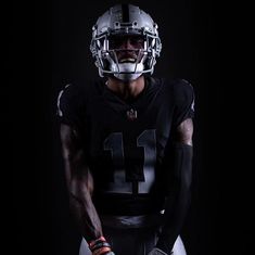 a football player wearing a helmet and holding his hands in the air while standing against a black background