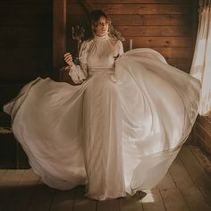 a woman in a white dress is posing for the camera with her long flowing skirt