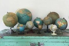 several globes sitting on top of an old dresser