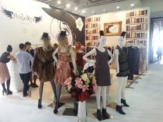 a group of mannequins are standing in front of a book shelf with books