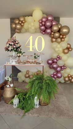 a table topped with lots of balloons and greenery next to a sign that says 40