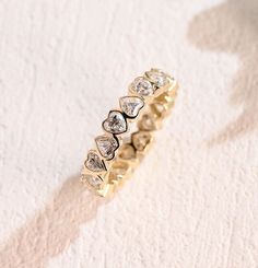 a gold ring with five hearts on it and two diamonds in the middle, sitting on a white surface