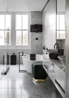 a large white bath tub sitting in a bathroom next to two sinks and a mirror