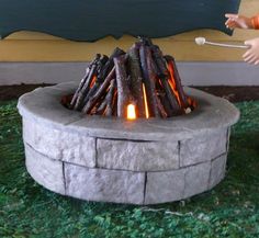 a fire pit made out of concrete with logs on the bottom and flames coming out of it