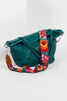 a green purse with a colorful floral print strap