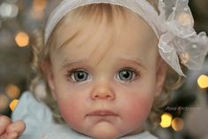 a close up of a baby wearing a white dress