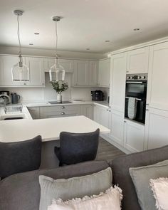 a kitchen with white cabinets and gray couches