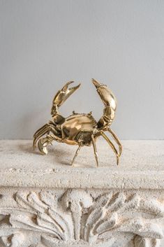 a gold crab statue sitting on top of a marble slab