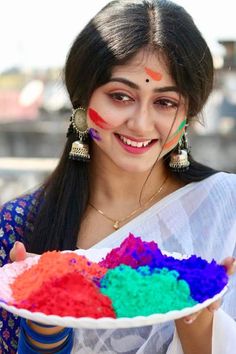 a woman holding a plate with colorful powder on it