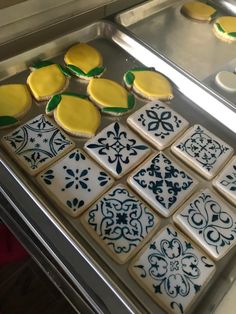 some decorated cookies sitting on top of a metal tray in front of a pan filled with cupcakes