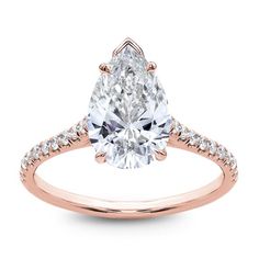 a rose gold engagement ring with a pear shaped diamond in the center and pave set shoulders