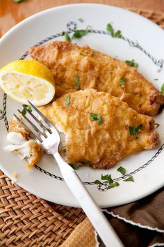 two pieces of fried fish on a plate with a fork